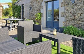 Eine Terrasss mit Korbmöbeln, einem Tisch und einer Laterne.