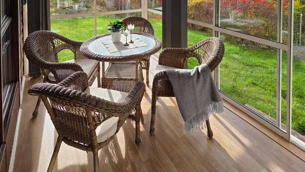 A wicker dining set with a glass table and chairs, a potted plant, and a view of a garden through large windows. - 1 bedroom awesome home in Boxholm (Boxholm)