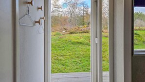 A doorway leading to a wooden deck with a view of a grassy area and trees. - 1 bedroom awesome home in Boxholm (Boxholm)