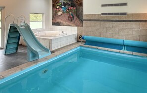 Une piscine avec un toboggan, un jacuzzi et une fresque représentant un paysage tropical.