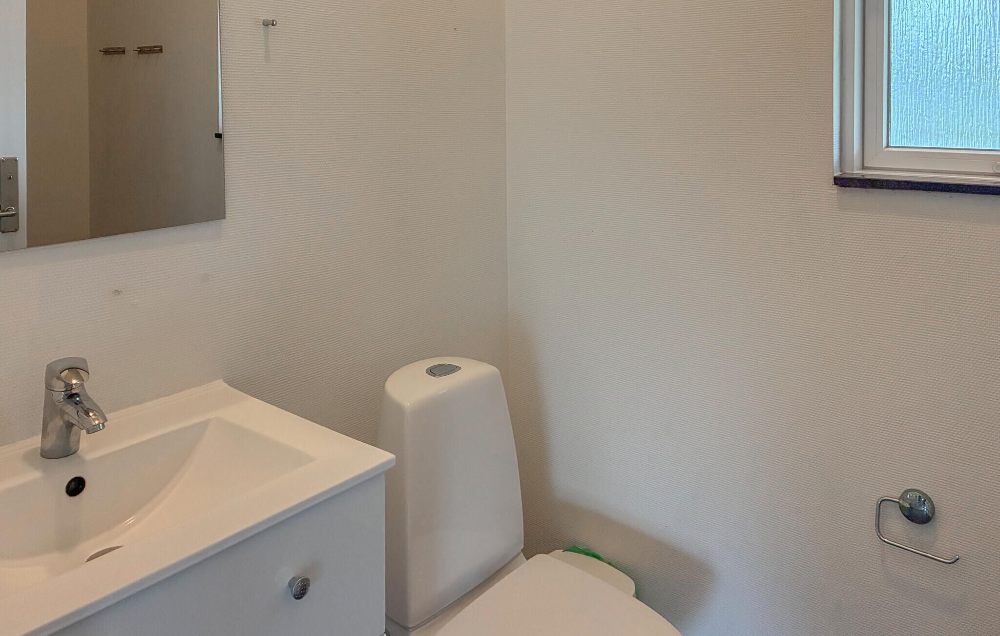 Une salle de bain avec un lavabo blanc, des toilettes et un distributeur d’essuie-tout.