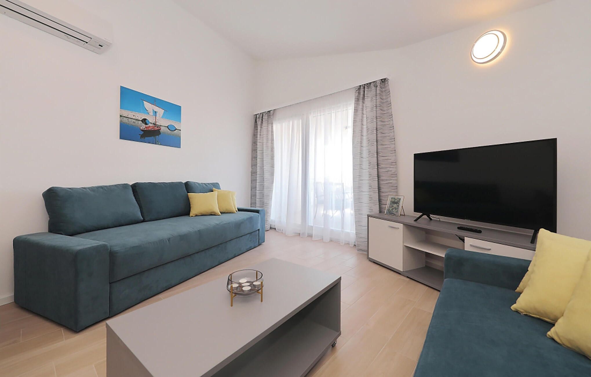 Ein modernes Wohnzimmer mit einer Couch, einem Couchtisch, einem Fernseher und einem Bild an der Wand.