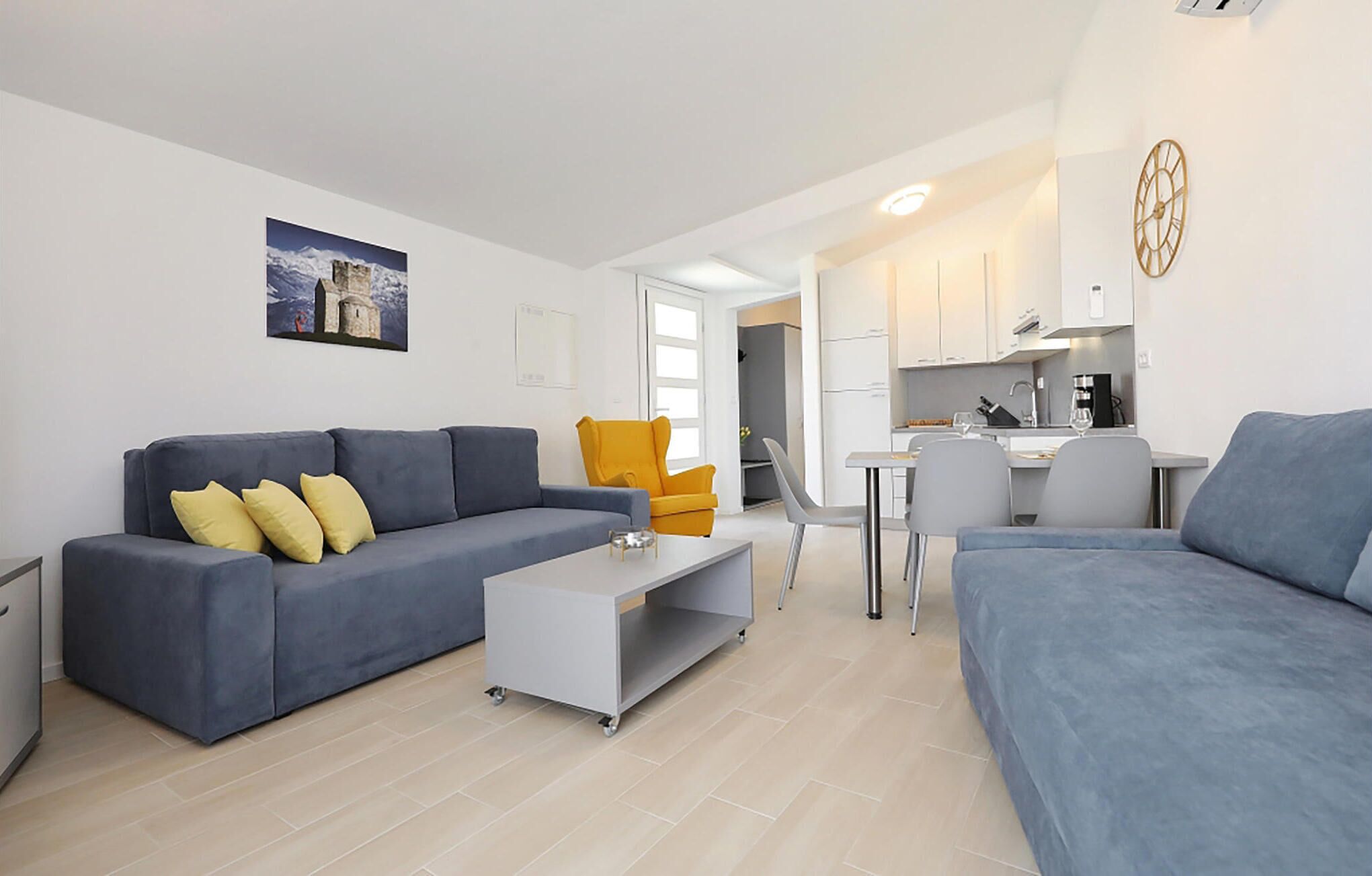 A modern living room with a grey sofa, a yellow armchair, and a dining area with a table and chairs.