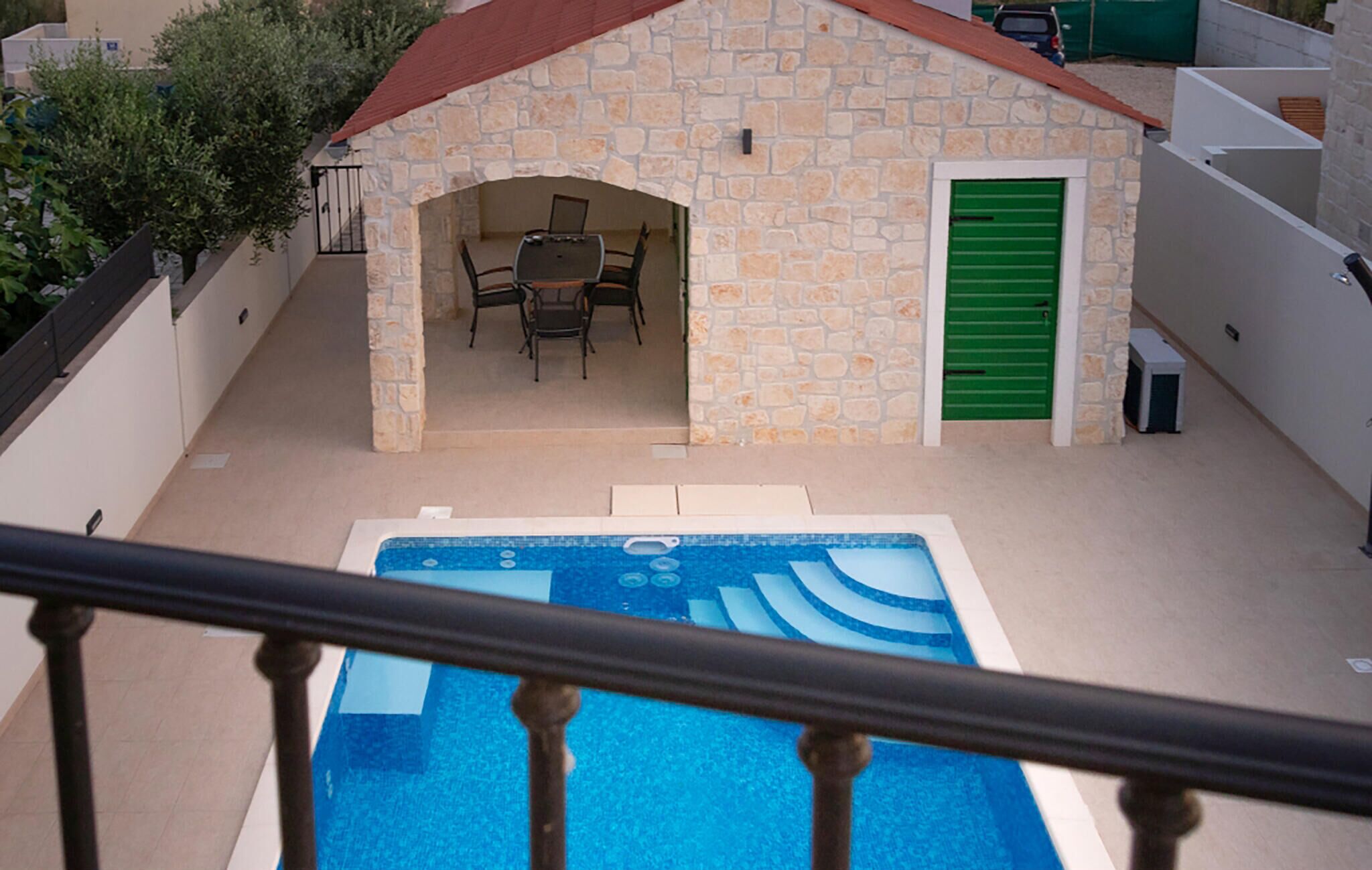 A stone building with a pool, a table, and chairs outside.