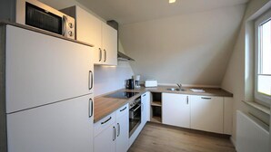 Eine kompakte Küche mit weißen Schränken, einer Mikrowelle, einer Kaffeemaschine und einem Toaster.