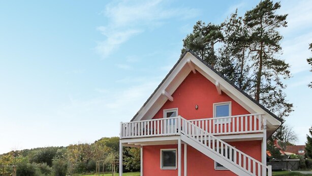 Ein zweistöckiges Haus mit roter Fassade und weißen Balkonläufen.
