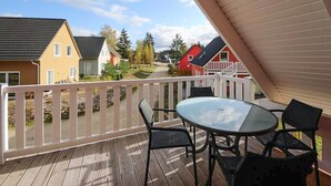 Eine Holzterrasse mit Glastisch und Stühlen, mit Blick auf eine Wohngegend mit Häusern und Bäumen.