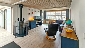 Una sala de estar moderna con chimenea, un sofá, un escritorio con un globo terráqueo y un ventanal grande.