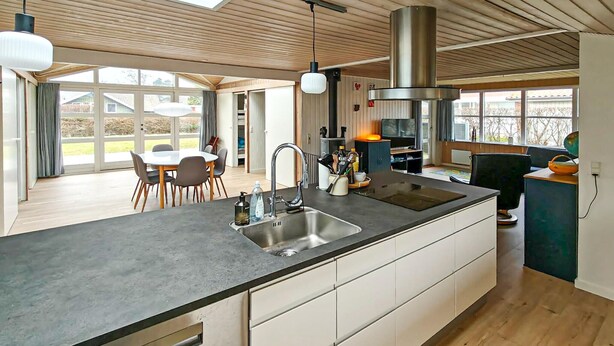 Una cocina moderna con una isla grande, electrodomésticos de acero inoxidable y una zona de comedor con mesa y sillas.