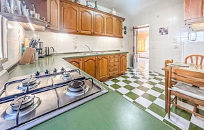 Une cuisine avec des meubles en bois, une cuisinière à gaz et un carrelage à motifs carrés.