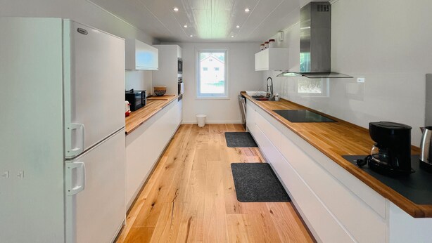 Een moderne keuken met witte kasten, een houten aanrechtblad en een roestvrijstalen afzuigkap.