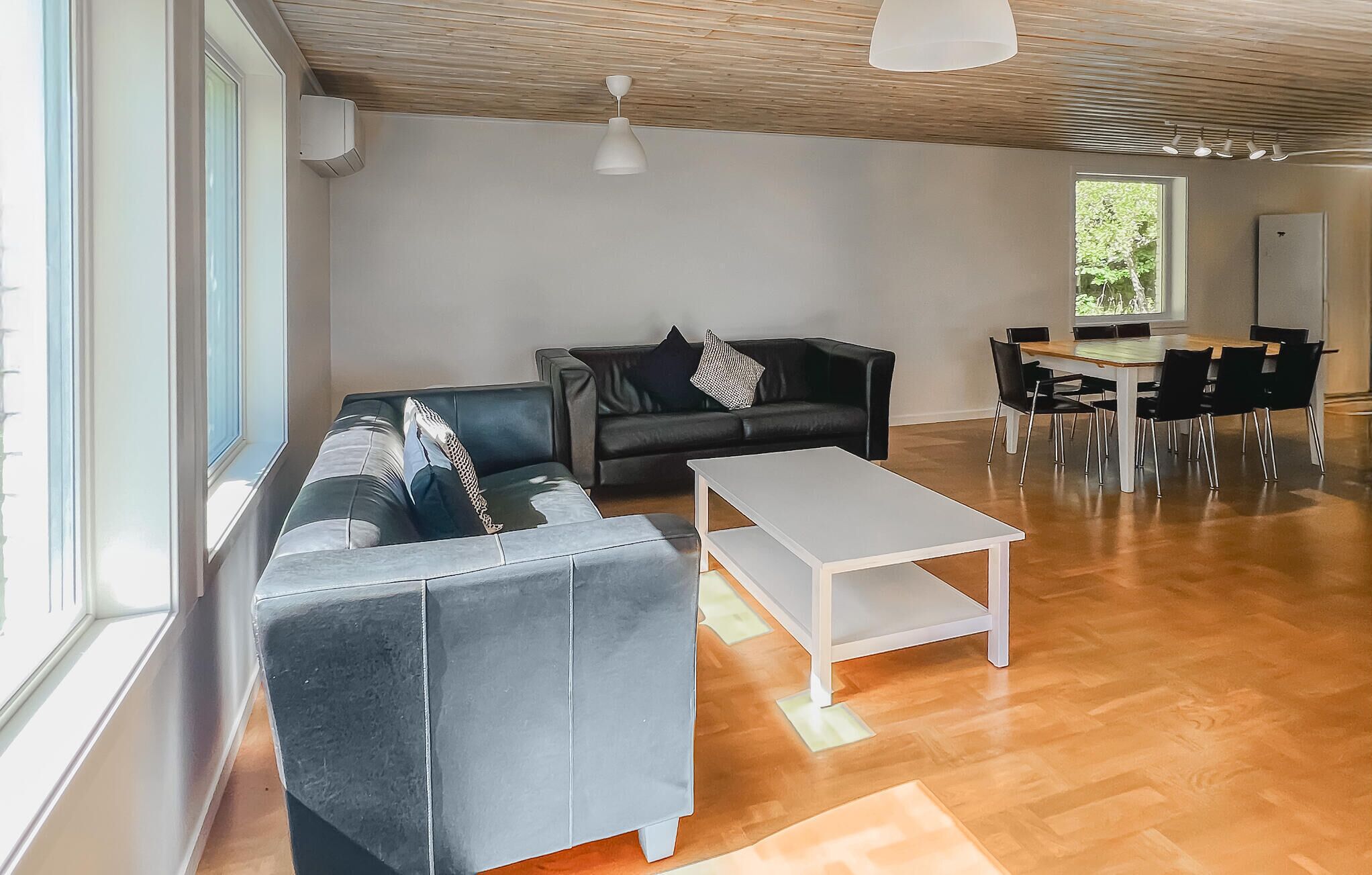 A modern living room with a grey sofa, a white coffee table, and a dining area with a wooden table and chairs.