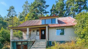 Een tweelaags huis met een pannendak, een balkon en een trap naar de ingang.