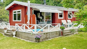 A red wooden cabin with a white porch, a small deck, and outdoor seating. - Lovely home in Asnæs with WiFi (Asnæs)
