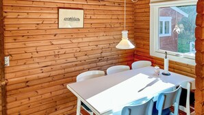 A wooden cabin interior with a white table and chairs, a hanging light fixture, and a framed picture on the wall. - Lovely home in Asnæs with WiFi (Asnæs)