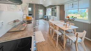 A kitchen with a wooden table and chairs, a sink, and a window with a view of the countryside. - Awesome home in Mariestad with WiFi (Mariestad)