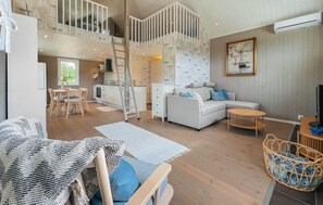 Un vaste espace de vie comprenant un salon avec une chambre en mezzanine, un coin repas et une cuisine.