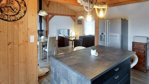 Eine moderne Küche mit einer zentralen Kochinsel, Holzwänden und einem Essbereich mit einer Couch und Stühlen.