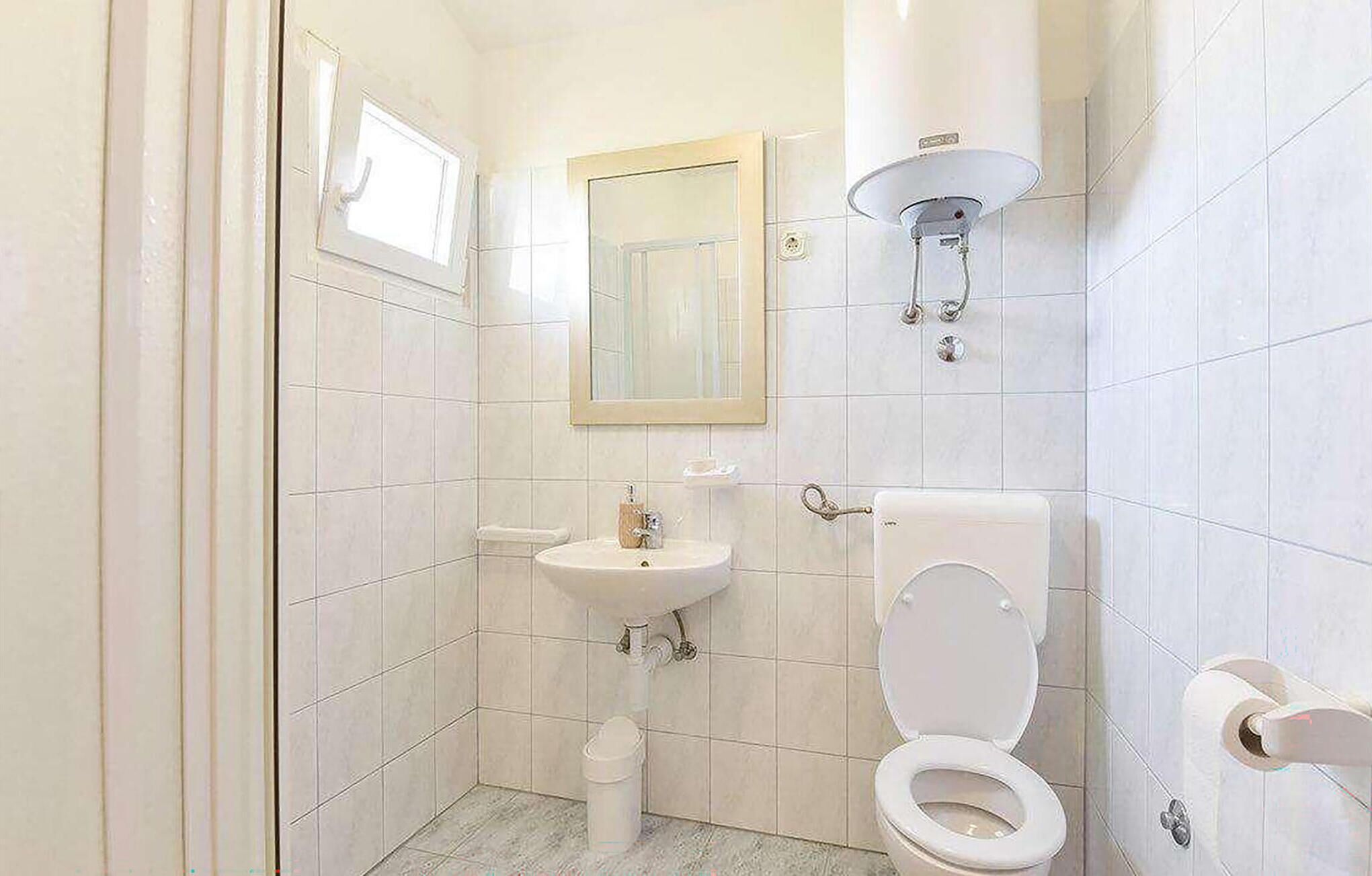 A small bathroom with a toilet, sink, and mirror.