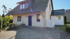 A two-story house with a tiled roof, a front door, and a small porch area.