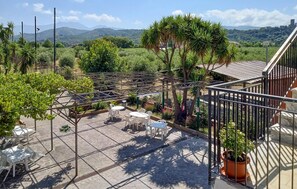 Eine Terrasse mit einer Pergola, Sitzgelegenheiten im Freien und Blick auf eine Berglandschaft.