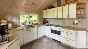 A kitchen with white cabinets, a stove, and a sink. There is a window with a view of greenery outside. - Awesome home in Tarm with sauna (Tarm)