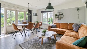 A spacious living room with a large window, a dining area, and a cozy seating area with a sofa and coffee table. - Beautiful home in Paasloo with sauna (Paasloo)