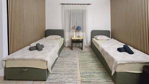 A room with two single beds, a small table with a lamp, and a curtain. - House with heated pool (Bribir)