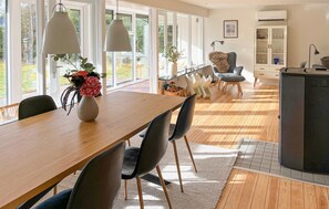 Een ruime eethoek met een lange houten tafel, zwarte stoelen en hanglampen.
