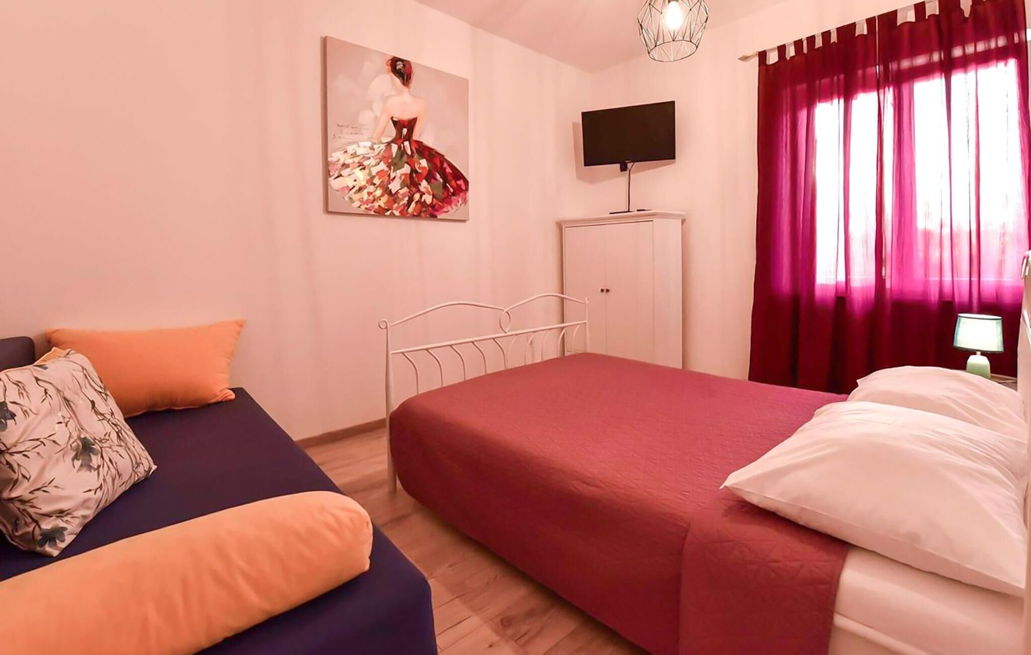 A bedroom with two beds, a television, and a wardrobe.