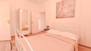Un dormitorio con cama, mesita de noche, espejo y puerta.