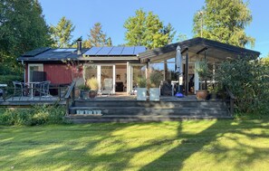 Een huis met een overdekte veranda, zonnepanelen en een tuin.