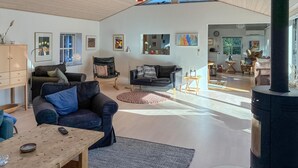 Een ruime woonkamer met een open haard, een eethoek en uitzicht op de keuken.
