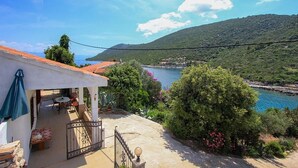 Una propiedad costera con patio, vista al mar y montañas de fondo.