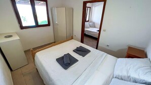 Una habitación pequeña y limpia con una cama, un armario y un escritorio.