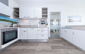 A modern kitchen with white cabinets, a built-in oven, and a countertop with various appliances. - Pet friendly apartment in OstseeOlpenitz with sauna (OstseeOlpenitz)