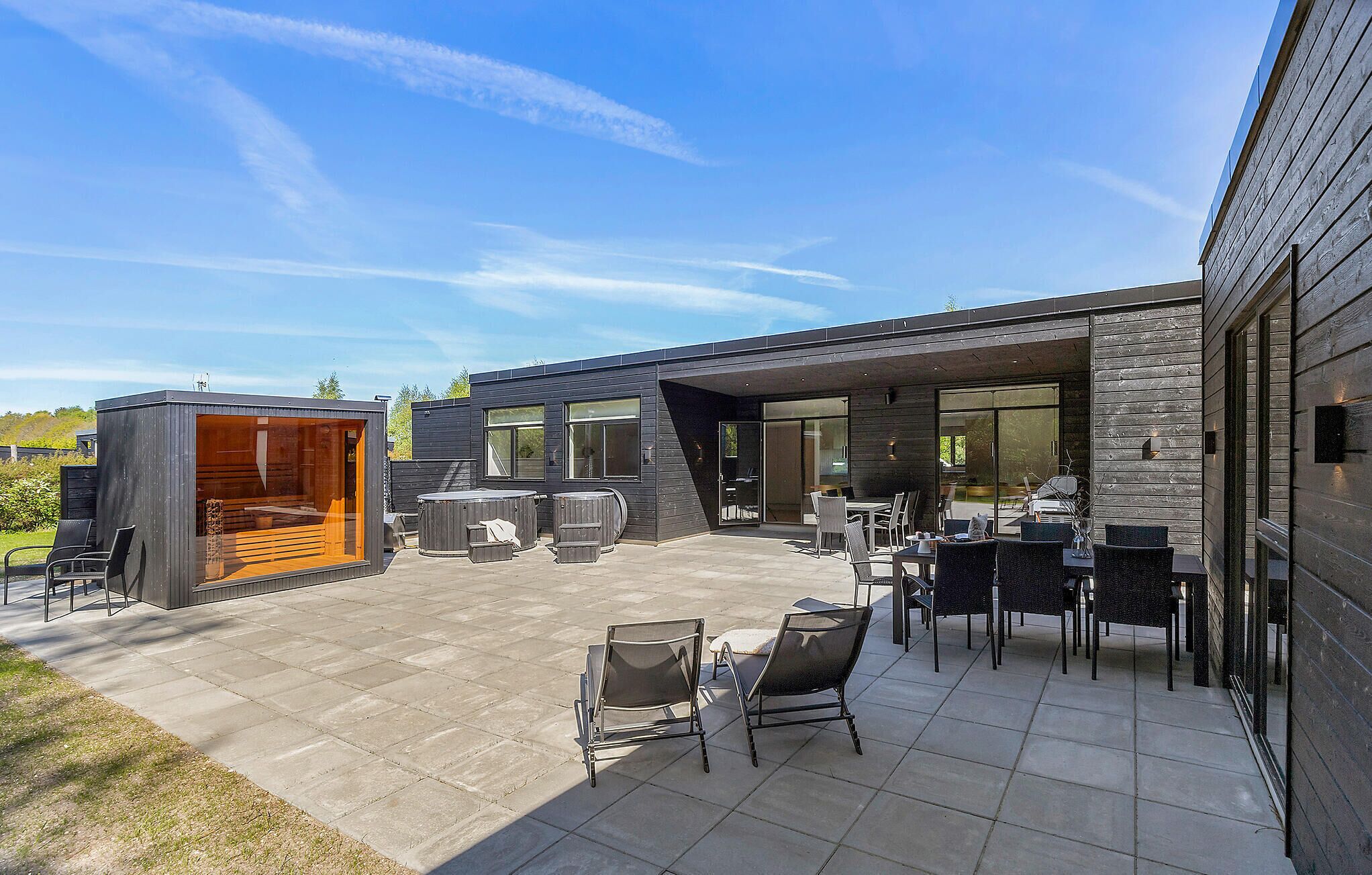 A modern outdoor patio with seating and a hot tub.