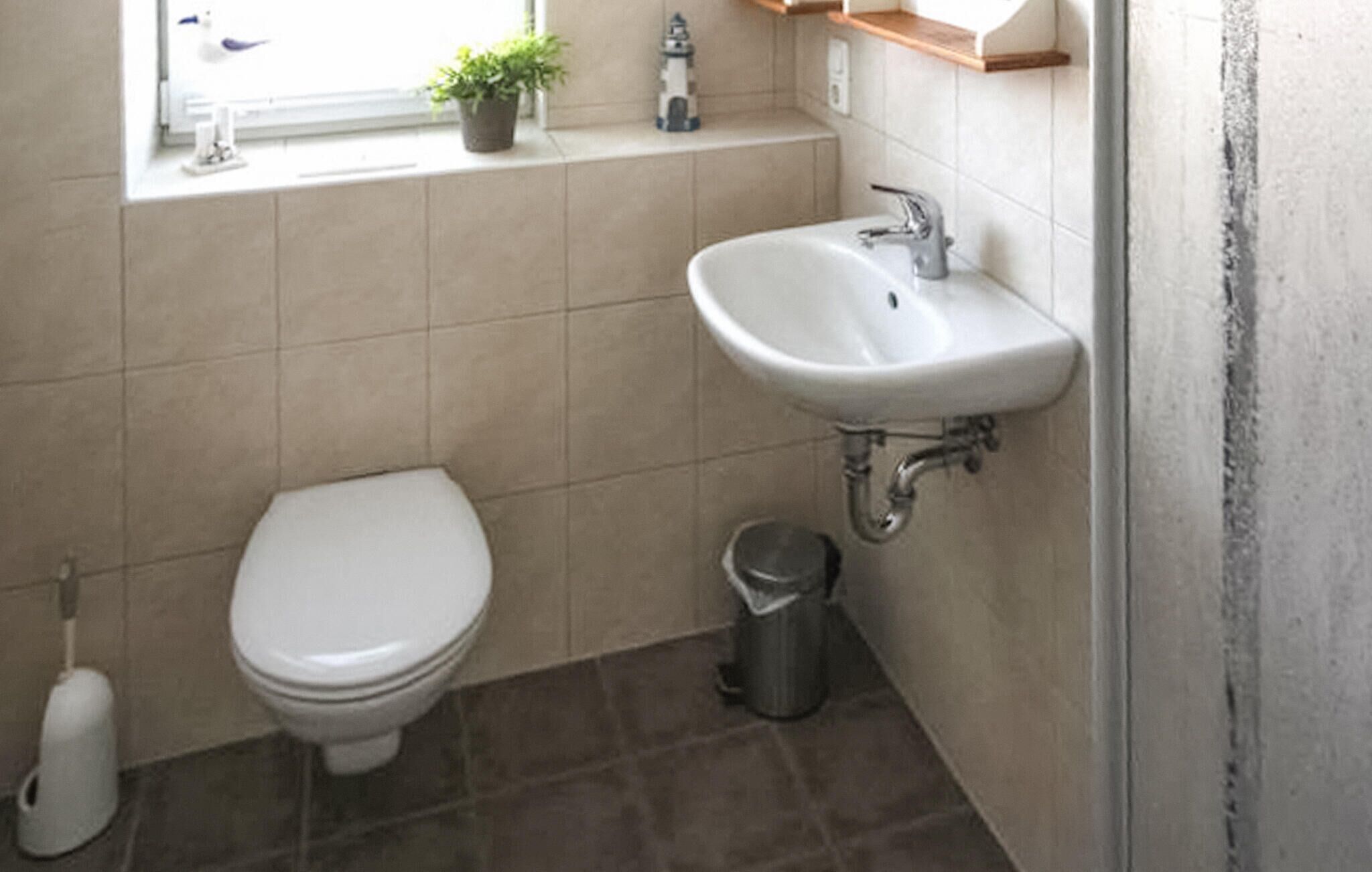 Een kleine badkamer met toilet, wastafel en prullenbak.