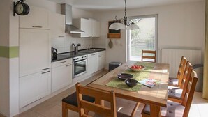 Une cuisine moderne avec des meubles blancs, une cuisinière et une table à manger avec des chaises.