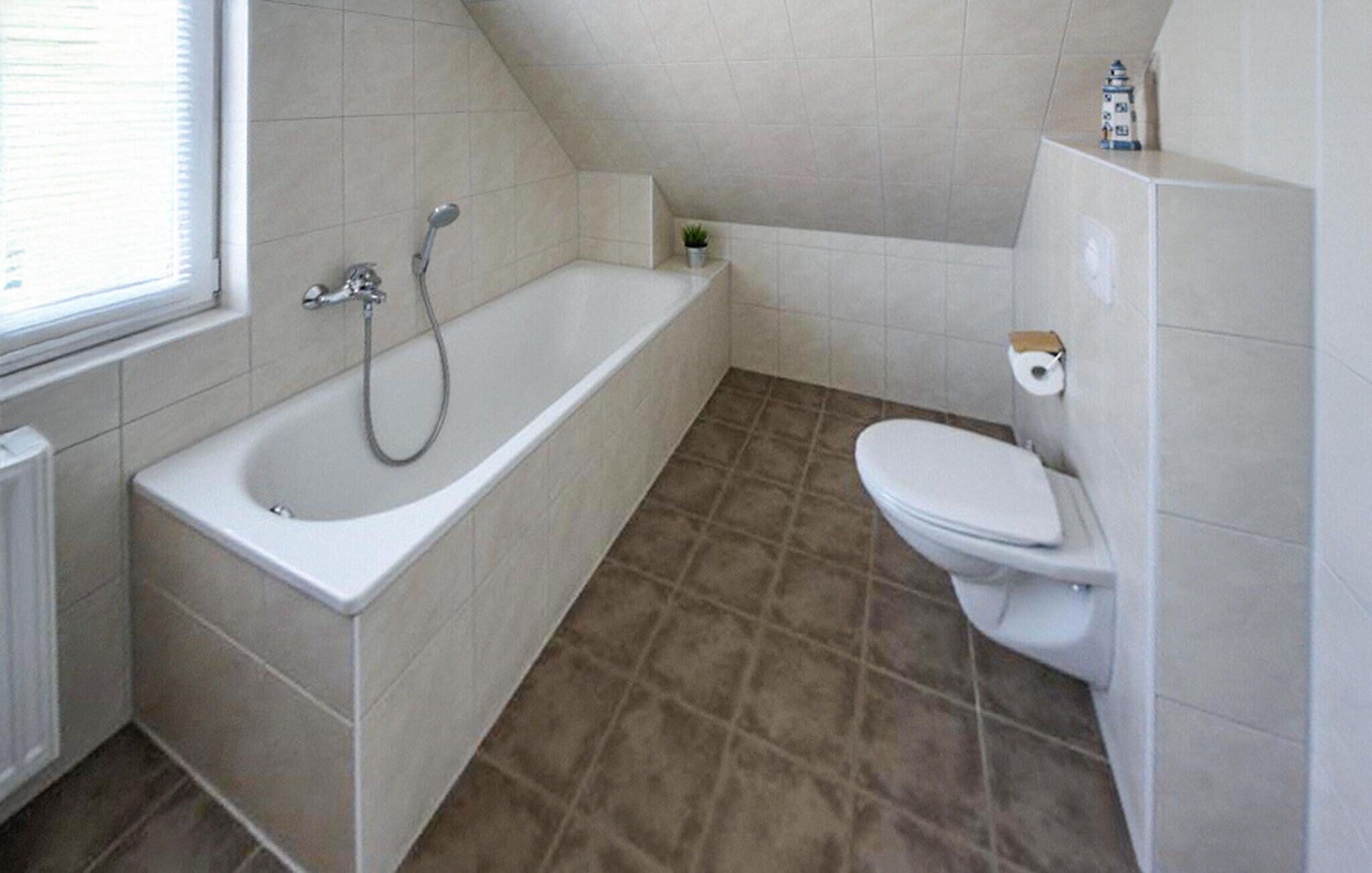 Un bagno con vasca, WC e una piccola finestra.