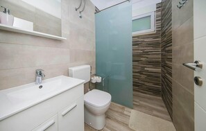 Een moderne badkamer met een wit wastafel, toilet en douchegedeelte.