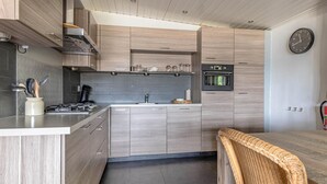 Eine moderne Küche mit Holzausstattung, einem Backofen und einer Kaffeemaschine.