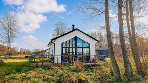Una casa moderna con ampie finestre, immersa nel verde e circondata da un prato.