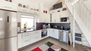 Una cucina moderna con mobili bianchi, elettrodomestici in acciaio inossidabile e un'isola centrale.