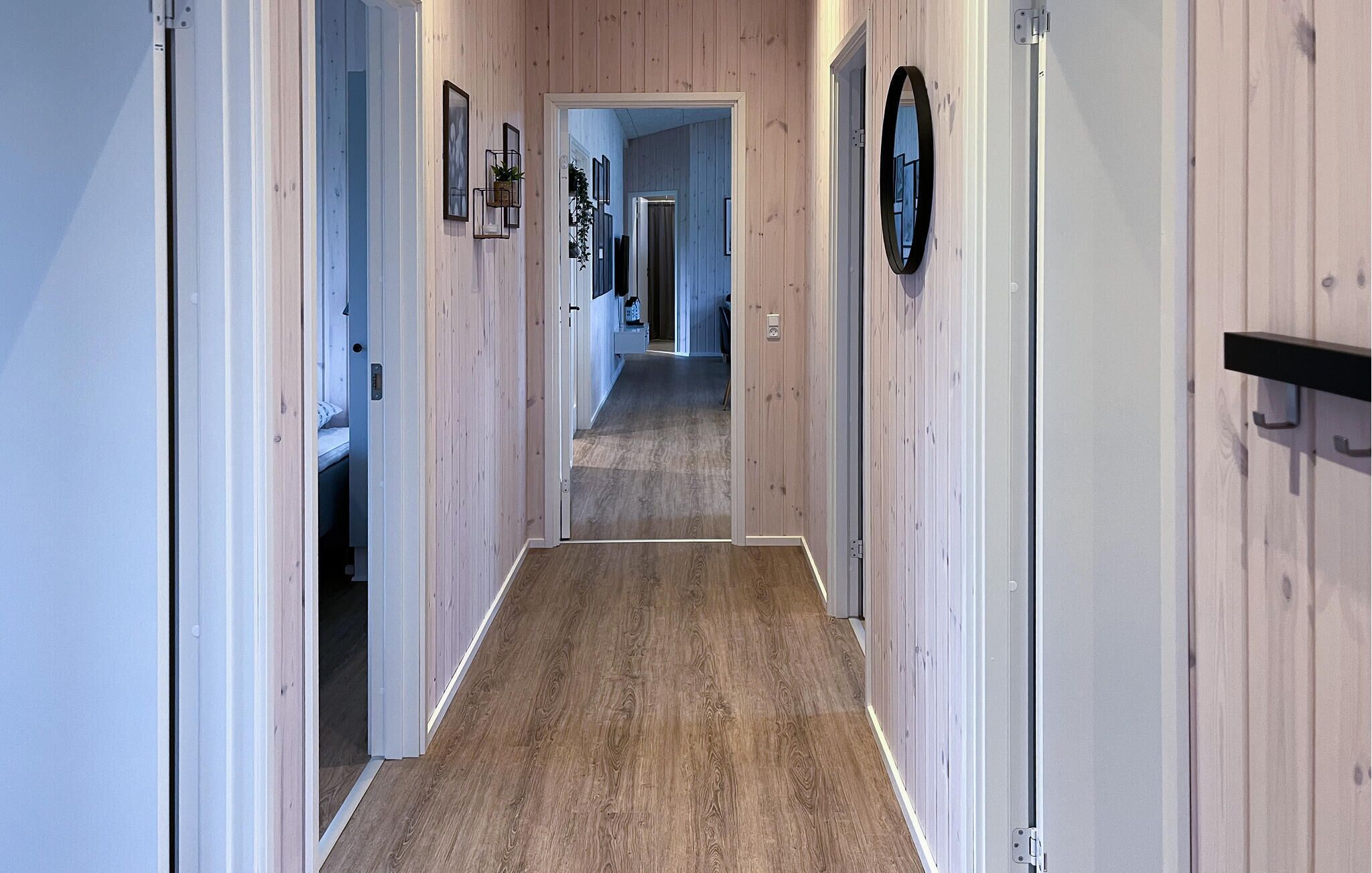 Un pasillo con paredes y suelos de madera que conduce a un dormitorio con cama y baño.