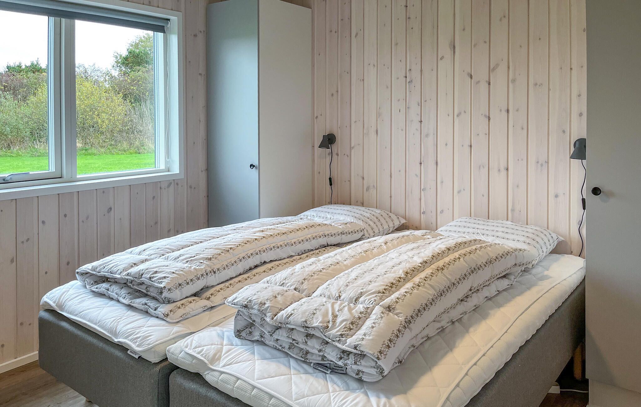 A bedroom with a bed, a window, and wooden panel walls.
