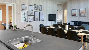 Une cuisine moderne dotée d’un grand îlot central, d’un évier intégré et d’un coin repas avec une table et des chaises.