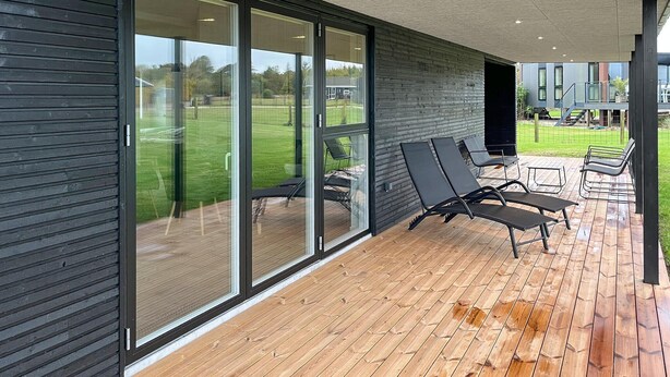 Une terrasse extérieure moderne, dotée de portes-fenêtres coulissantes qui donnent sur une cour verdoyante.