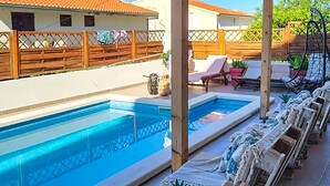 Ein Schwimmbecken mit Liegestühlen und einem Holzzaun.
