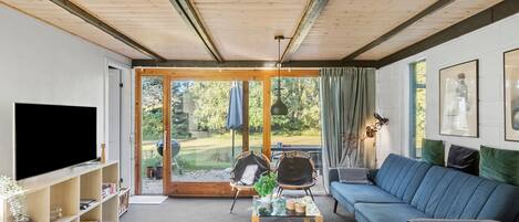 Uma sala de estar moderna com televisão, sofá e mesa de jantar.
